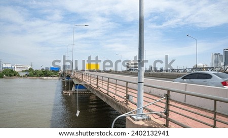 Picture of a bridge over a river with clear lane division There is a barrier between the dirt zone and the driving zone during the day. And there are lights from electric poles that shine brightly 