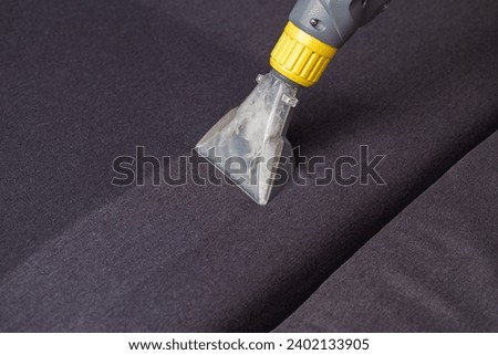 Cleaning the sofa with a special washing vacuum cleaner from dirt. Dry cleaning of sofas and upholstered furniture, close-up Royalty-Free Stock Photo #2402133905