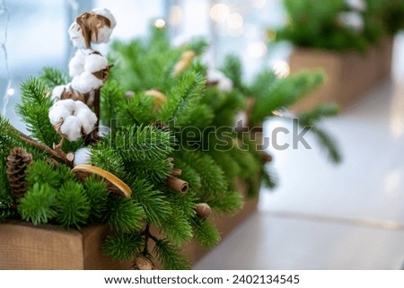 Christmas tradition decoration on a windowsill in a cafe. Spruce needles, cinnamon, cotton in wooden box, selective focus.