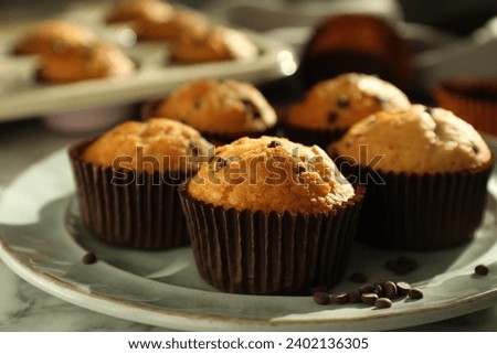 Delicious sweet muffins with chocolate chips on white marble table, closeup