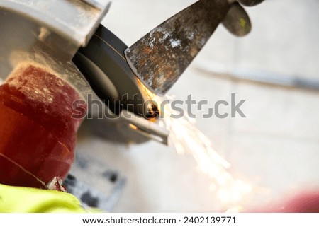 Sharpening a Spatula Work Tool on the Electric Sander Close Up with Sparks Indoor