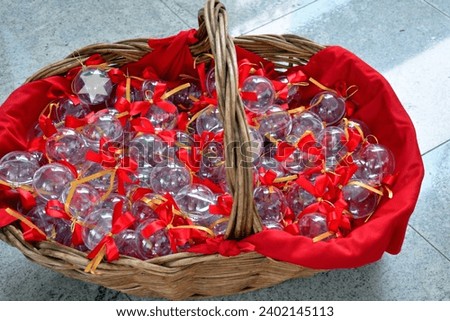 Plastic Christmas baubles with red ribbons in a wicker basket.
