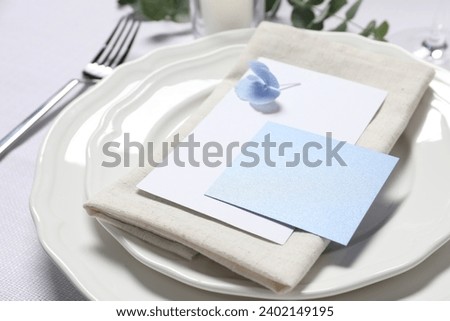 Beautiful table setting with blank card and floral decor, closeup