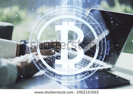Double exposure of creative Bitcoin symbol with hands typing on laptop on background. Cryptocurrency concept