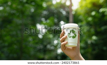 Hand holding a paper cup with symbols recycle or recycling arrows flat icon, Ecology and save the earth concept. green background Royalty-Free Stock Photo #2402173861