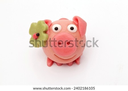 Lucky pig made of marzipan with shamrock and ladybug as a symbol of luck in close-up against a neutral white background Royalty-Free Stock Photo #2402186105