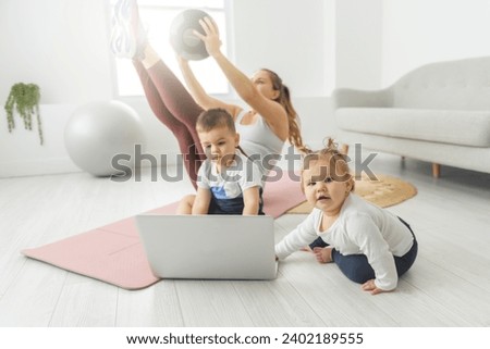 A Sport Activities With Baby. Young Mom trying doing Exercising With Her Infant Son At Home