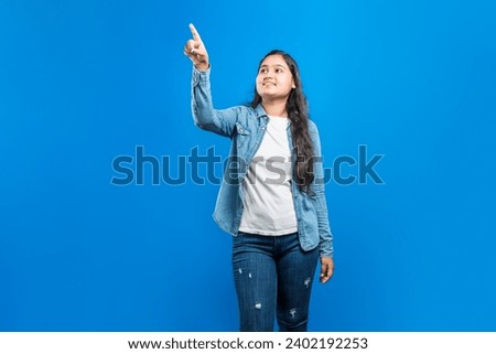 Caucasian female looking up and pointing finger upwards