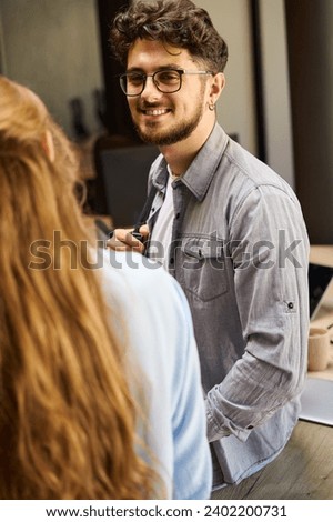 Smiling businessman looking at cropped businesswoman on table in office