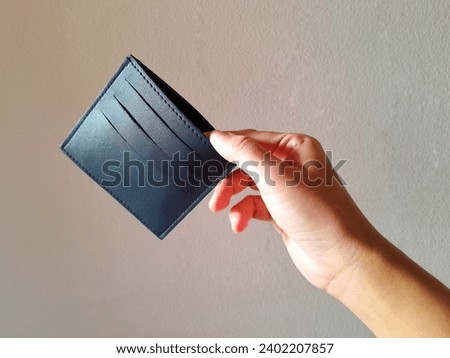 Woman's hand holding empty blue credit card holder isolated on white background.