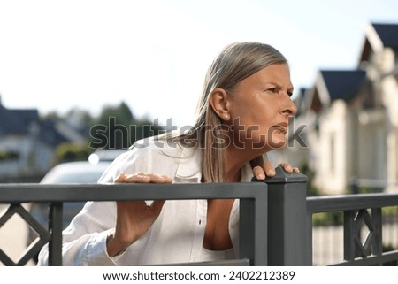 Concept of private life. Curious senior woman spying on neighbours over fence outdoors Royalty-Free Stock Photo #2402212389