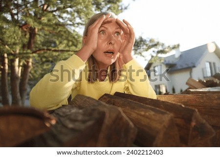 Concept of private life. Curious senior woman spying on neighbours over firewood outdoors Royalty-Free Stock Photo #2402212403