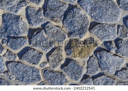It is a view of grey stone wall. It is photo of gray pavement. It is blue stones