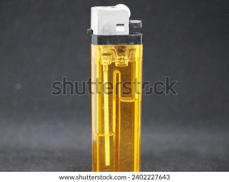 A close-up view of an unbranded yellow gas lighter on a black background