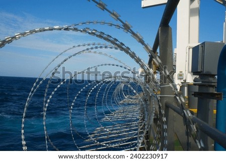 View of the vessel hardening on board ships using razor wire and spikes, to stop pirates from boarding the ship. These ship protection measures are employed when the ship passes high risk areas Royalty-Free Stock Photo #2402230917