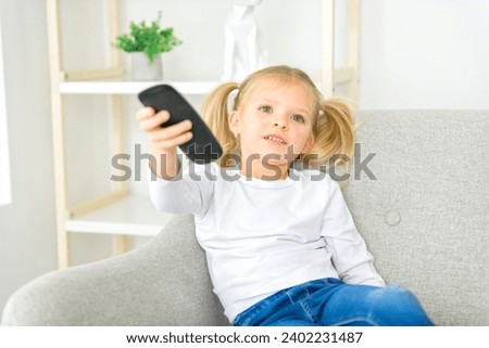 A Blond girl holding remote control on sofa at home