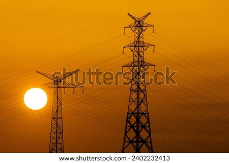 Negative effect of solar flare on electrical energy idea concept. Electric pylon and the yellow sun disk setting behind it. Natural and sustainable energy sources. Power line silhouette at sunset.