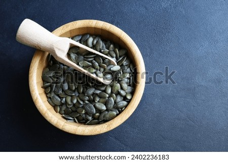 Natural green pumpkin seeds without shell isolated on dark background. Healthy food concept. Overhead view. Copy space. Royalty-Free Stock Photo #2402236183