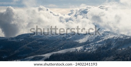 Cumulus clouds float gracefully over the snow-capped mountain ranges, painting a serene winter landscape. Scene against the backdrop of Christmas and New Year