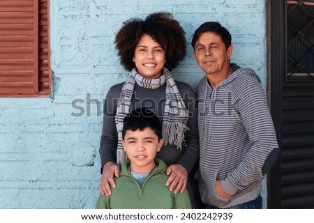 Happy brazilian grandchild with mother and grandfather embracing each other outside the house. Relationship, leisure, enjoyment concept. Royalty-Free Stock Photo #2402242939