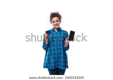 young beautiful european woman with curly hair dressed in a blue plaid shirt holds a discount card and a smartphone