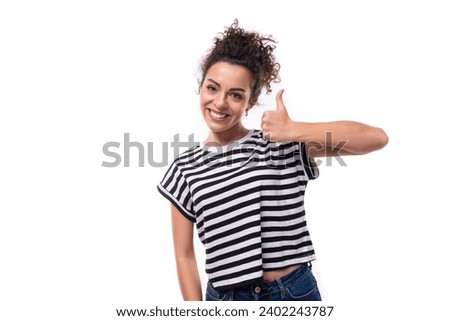 young joyful caucasian woman with curly black hair is dressed in a striped black and white t-shirt against the background with copy space