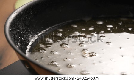 Used Cooking Oil in Frying Pan with bubbles. Close-up, shallow dof. Royalty-Free Stock Photo #2402246379