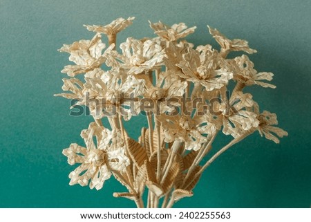The flowers is made of straw on a green background in a cardboard vase. Straw weaving