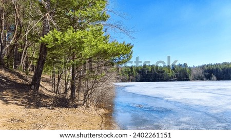 Landscape with lake covered with ice before the start of melting and ice drift on spring day with the sun. Blue ice and water under sunlight in early spring or autumn