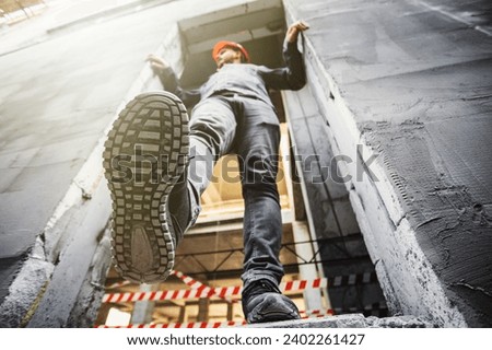 Builder man near an unfenced dangerous opening at a height at a construction site. Violation of safety regulations at a construction site. Royalty-Free Stock Photo #2402261427