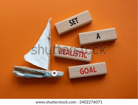 Set a realistic goal symbol. Concept words Set a realistic goal on wooden blocks. Beautiful orange background with boat. Business and Set a realistic goal concept. Copy space.
