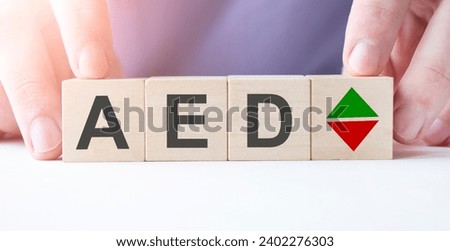 Businessman hand holding wooden cube block with aed business word on table background.