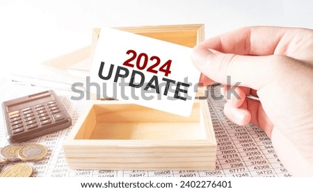 Businessman hold white card with text 2024 update Calculator, wood box, money and financial documents