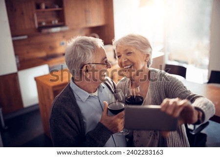 Happy senior couple toasting with wine taking picture at home