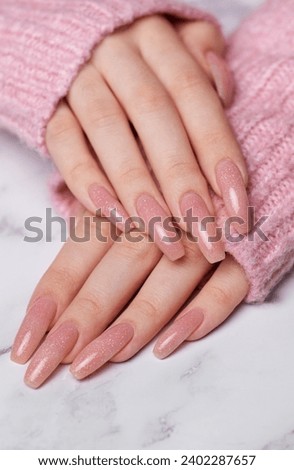 Female hands with pink nail design.  Pink nail polish manicure on marble background. 