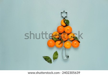 Christmas concept, tangerines laid out in the shape of a Christmas tree on a plain green background. Merry Christmas
