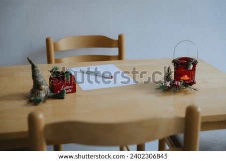 A sheet of paper, a pen and Christmas decorations on a wooden table.