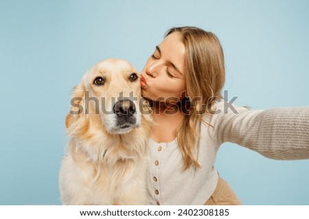 Close up young owner woman with her best friend retriever wear casual clothes do selfie shot on mobile cell phone kiss dog isolated on plain pastel light blue background. Take care about pet concept
