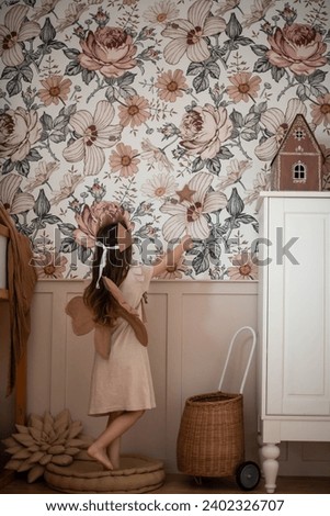  A girl in a crown and with wings plays in the Children's room. The interior with a canopy is beautiful in boho style. Royalty-Free Stock Photo #2402326707