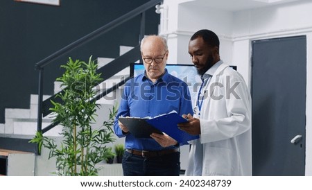 Specialist explaining disease expertise to elderly patient during checkup visit consultation in hospital waiting area. Senior man man filling medical insurance documents, medicine service