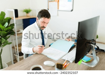 Caucasian businessman signing a new contract at his office and working as a lawyer or attorney sitting at his desk