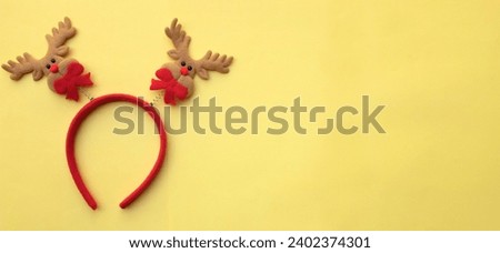 cute Christmas headbands with christmas reindeer horns isolate on a yellow pastel backdrop. concept of joyful Christmas party,New year is coming soon, festive season decoration with Christmas elements