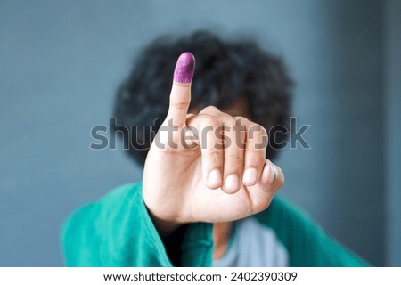 Man showing little finger after voting on Indonesia's presidential election Royalty-Free Stock Photo #2402390309