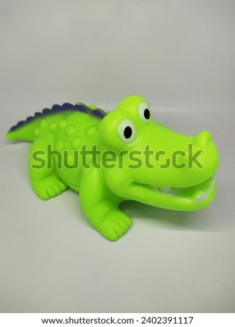 photo of a light green crocodile toy with a white background, side view, made of rubber and safe for children