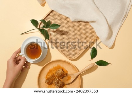 Round wooden dish featured cubes of beeswax. Hand model holding a teacup. Bamboo tray with blank space for product promotion