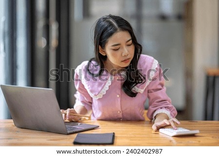 Photo of cheerful joyful young asian business woman in the office working on laptop digital project sitting at desk.