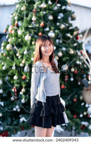 Merry x-mas,smile happiness portrait beautiful young asian woman wearing warm clothes on Christmas tree light circular bokeh background Decoration During Christmas and New Year Festival illumination.