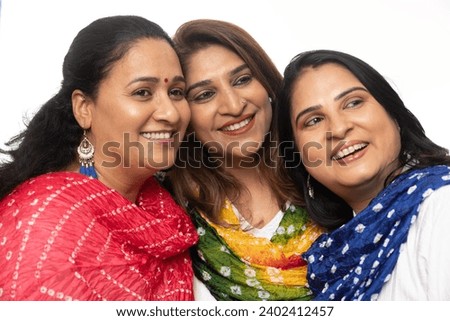 Three happy woman friends stating together showing woman unity, woman empowerment and woman health while looking at the camera isolated on white. Wearing white kurta and pajama on festive seasons