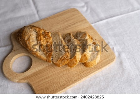 Rustic charm captured in sliced French bread on a wooden board. A simple yet inviting scene, showcasing the artistry of fresh, crusty baguette slices.