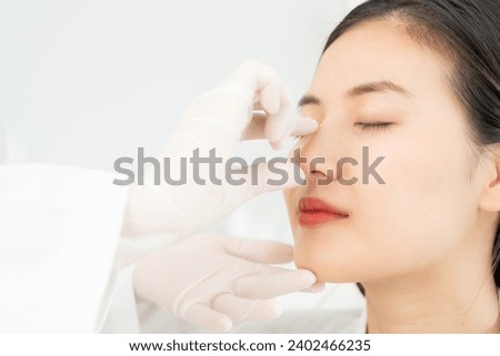 plastic surgery, beauty, Surgeon or beautician touching woman face, surgical procedure that involve altering shape of nose, doctor examines patient nose before rhinoplasty, medical assistance, health Royalty-Free Stock Photo #2402466235